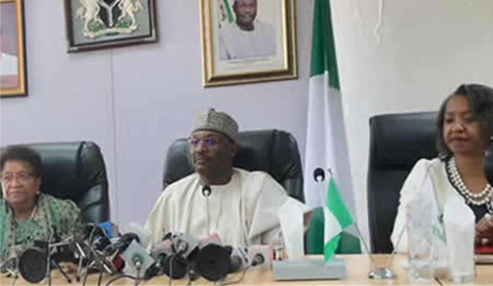 INEC Chairman flanked by two officers at media briefing