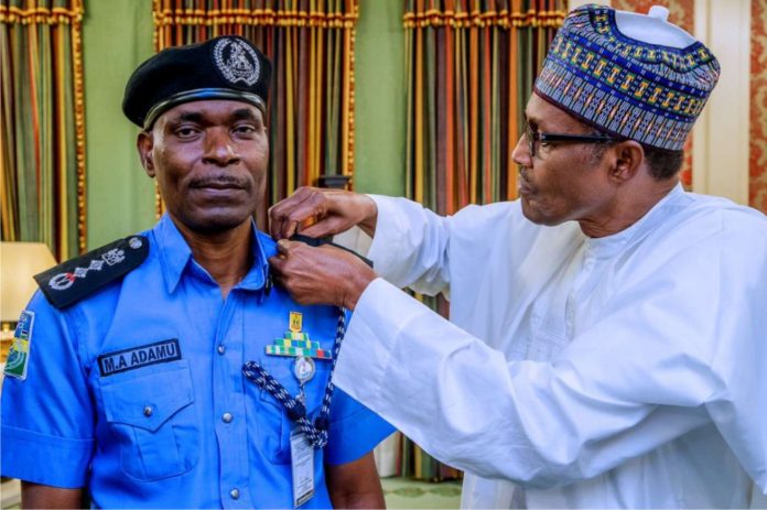 President Buhari decorating IGP Adamu with homour
